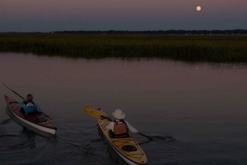 People kayaking during a full moon